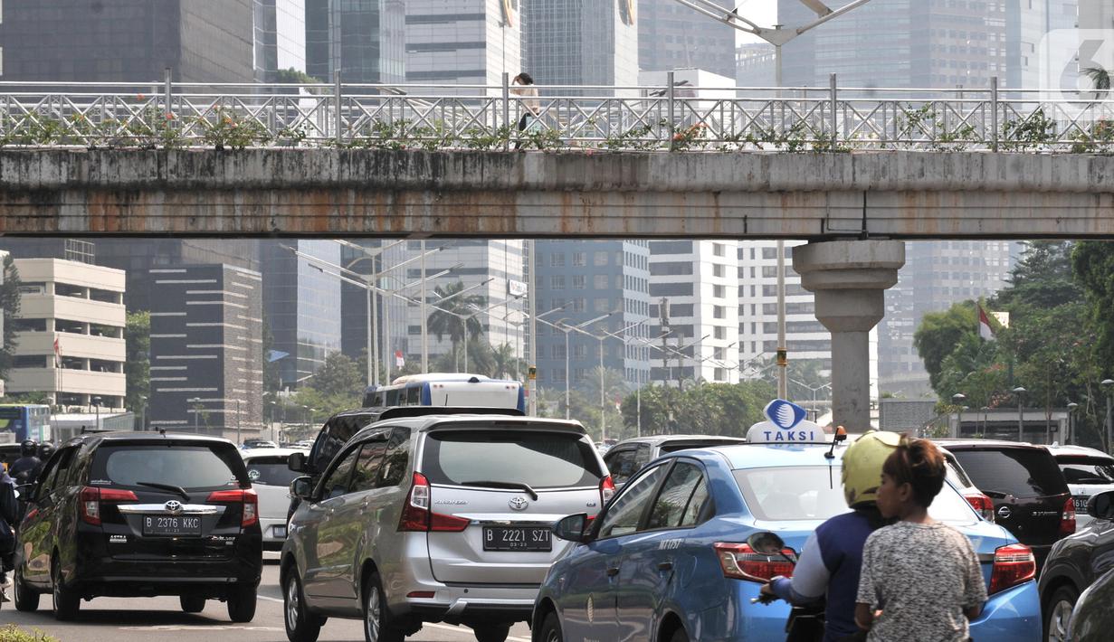 Kendaraan melintas di bawah jembatan penyeberangan orang (JPO) yang tidak beratap di jalan Sudirman, Jakarta,  Rabu (6/11/2019). Pemprov DKI melalui Dinas Bina Marga mencopot atap JPO Sudirman agar pejalan kaki dapat menikmati pemandangan gedung-gedung pencakar langit. (merdeka.com/Iqbal Nugroho)