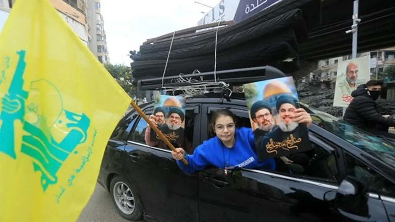 Warga Lebanon mengangkat potret pemimpin Hizbullah yang terbunuh, Hassan Nasrallah dan Hashem Safieddine, bersama dengan bendera kuning kelompok militan tersebut saat orang-orang kembali ke pinggiran selatan Beirut akibat gencatan senjata. (AFP)