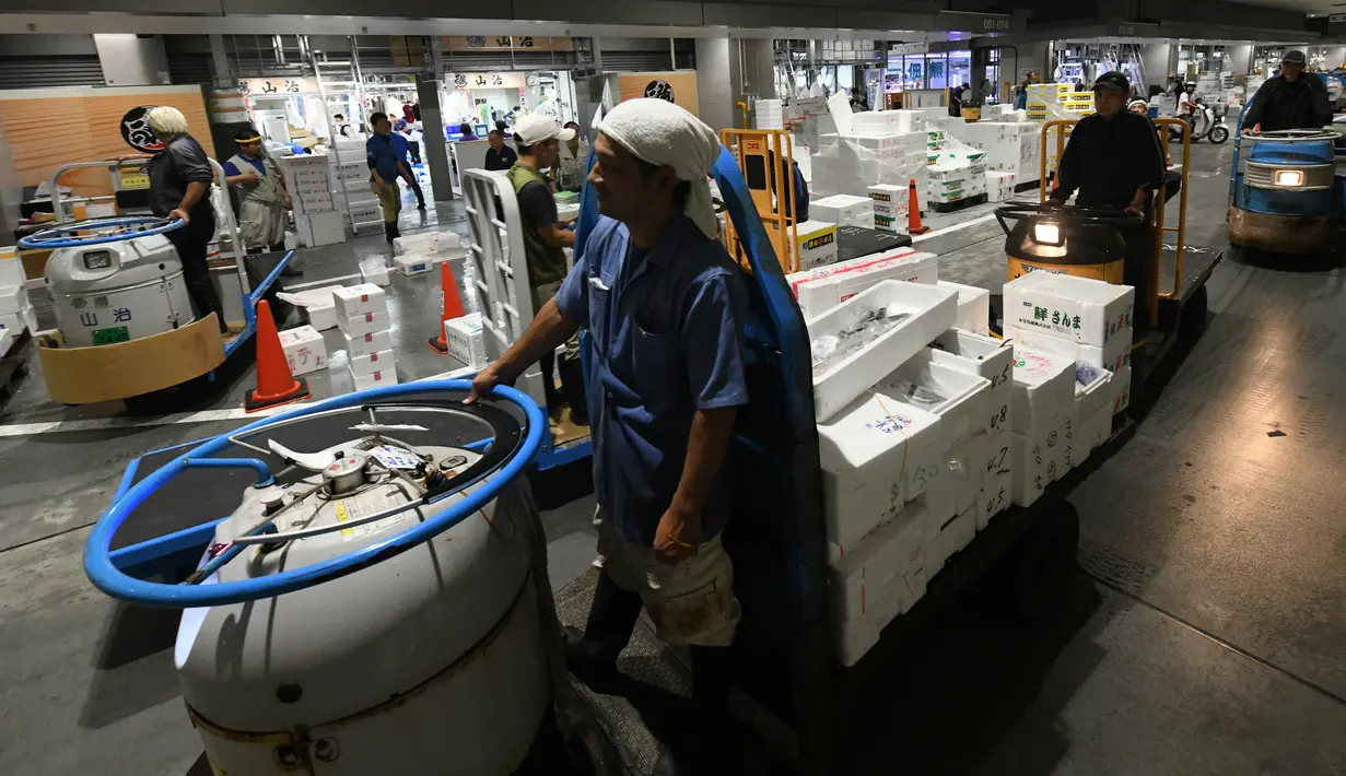 Pekerja mengoperasikan truk turret di antara toko-toko pada hari pertama pembukaan pasar ikan Toyosu yang baru,  di Tokyo, Kamis (11/9). Pasar ikan Toyosu menggantikan pasar ikan legendaris yang sudah mendunia, Pasar Tsukiji. (Toshifumi KITAMURA/AFP)