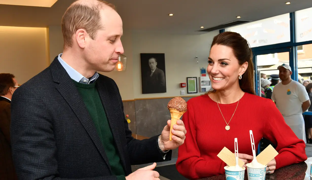 Kate Middleton tersenyum saat melihat Pangeran William mencicipi es krim selama mengunjungi Joe's Ice Cream di kawasan Mumbles, Wales Selatan, Selasa (4/2/2020). William dan Kate Middleton tengah dalam kunjungan ke kawasan Wales Selatan saat mampir ke Joe's Ice Cream. (ARTHUR EDWARDS/POOL/AFP)