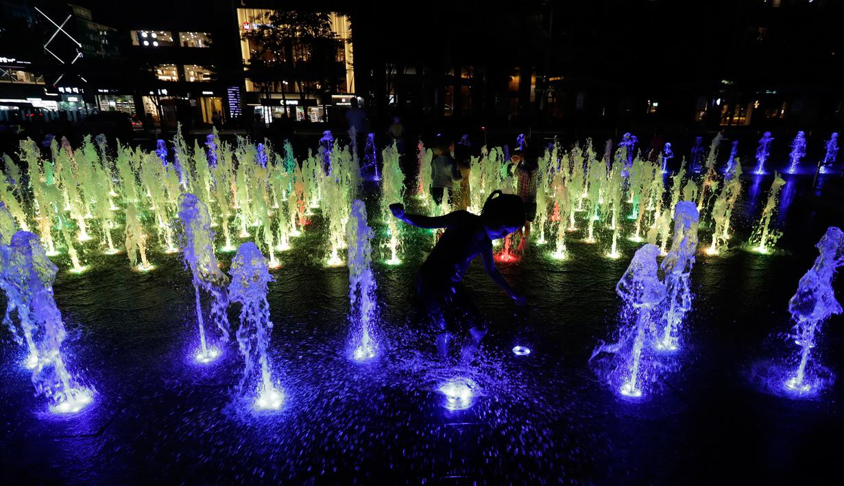 Anak-anak mendinginkan diri di air mancur yang berada di pusat Kota Seoul, Korea Selatan, Senin (23/7). Pekan lalu, gelombang panas menewaskan lima orang di Korea Selatan. (AP Photo/Lee Jin-man)