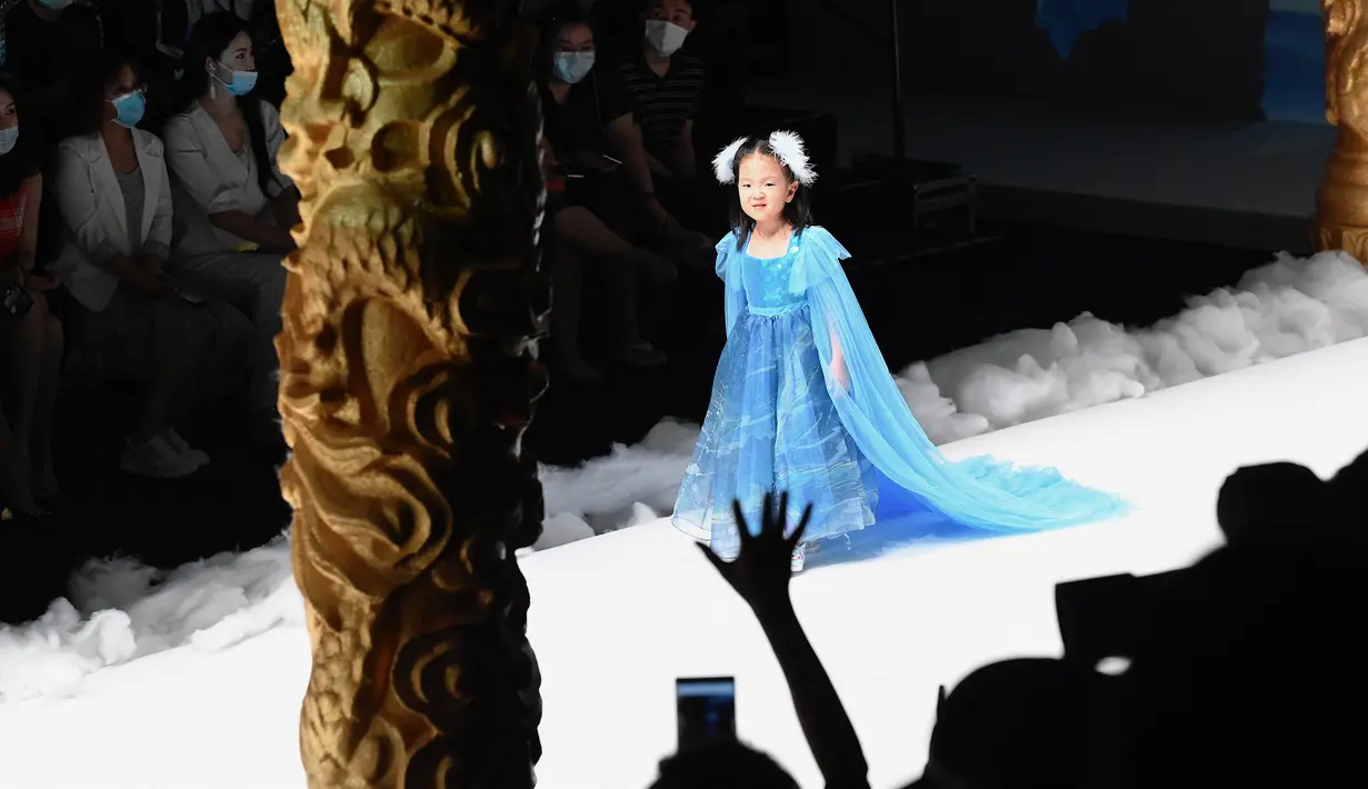 Seorang model cilik menampilkan kreasi dari koleksi Jinshangyuyi karya desainer Wang Cong selama China Fashion Week di Beijing pada Kamis (9/9/2021). Gelaran pekan mode tersebut tetap digelar di tengah pandemi corona covid-19. (Giok GAO / AFP)