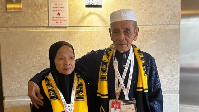 Rohmat, jemaah haji Indonesia yang merupakan seorang teman Tuli (kanan), dan istrinya, Masuah (kiri), yang merupakan penyandang disabilitas kognitif, saat ditemui di wilayah Aziziyah, Makkah, 16 Mei 2026. (Liputan6.com/Asnida Riani/Media Center Haji 2026)