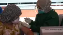 Petugas medis menyuntikkan vaksin covid-19 kepada seorang anak di Stadion Utama Gelora Bung Karno (GBK), Senayan, Jakarta, Sabtu (3/7/2021). Pemprov DKI menggelar vaksinasi COVID-19 massal bagi anak usia 12-17 tahun di Stadion GBK selama dua hari, yakni pada 3-4 Juli 2021. (merdeka.com/Imam Buhori)