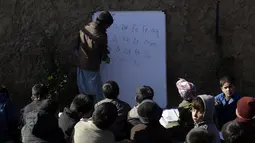 Anak-anak sekolah pengungsi Afghanistan menghadiri kelas di sekolah darurat di pinggiran Islamabad, Pakistan, Rabu (29/12/2021). (AP Photo/Rahmat Gul)