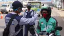 Petugas memeriksa suhu tubuh pengendara saat pelaksanaan Pembatasan Sosial Berskala Besar (PSBB) di kawasan Gading Serpong, Tangerang Selatan, Sabtu (18/4/2020). Pengukuran suhu tubuh tersebut merupakan cek point dari PSBB yang baru saja diberlakukan di Tangerang Raya. (Liputan6.com/Angga Yuniar)
