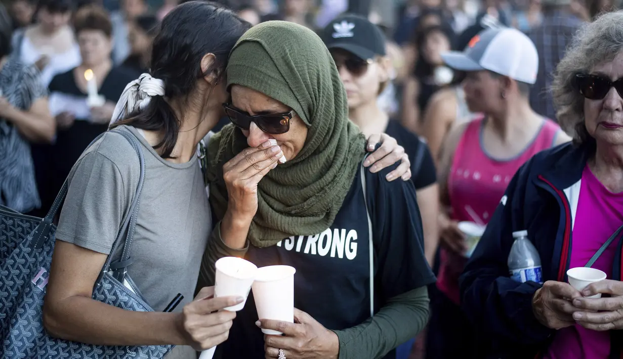 Seorang wanita dihibur rekannya saat menghadiri acara untuk korban penembakan brutal di festival kuliner Gilroy Garlic di Gilroy, California (29/7/2019). Pelaku merupakan remaja lelaki, Santino William Legan (19), menggunakan senapan serbu AK-47 saat melakukan aksinya. (AP Photo/Noah Berger)