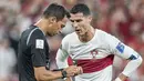 Megabintang Portugal, Crsitiano Ronaldo, berbincang dengan wasit Facundo Tello saat melawan Maroko pada laga babak perempat final Piala Dunia 2022 di Al Thumama Stadium, Sabtu (10/12/2022). (AP/Ariel Schalit)