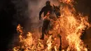 Seorang pria menunggangi kuda melewati api unggun saat festival Luminarias di San Bartolome de Pinares, Spanyol, Rabu (16/1). Festival ini digelar setiap tahunnya, sehari sebelum perayaan Santo Antonius yang merupakan pelindung binatang. (AP/Felipe Dana)