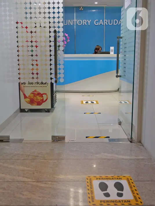 Tanda jaga jarak yang dipasang di lantai kantor  Suntory Garuda, Jakarta, Senin (8/8/2020). Suntory Garuda menerapkan protokol kesehatan, seperti kapasitas karyawan hanya dibolehkan sebanyak 50 persen, meniadakan absensi sidik jari dan menggunakan alat makan pribadi. (Liputan6.com/Herman Zakharia)