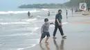 Wisatawan yang mengenakan masker bermain air saat mengunjungi Pantai Anyer di Cilegon, Banten, Minggu (25/10/2020). Akhir pekan dimanfaatkan warga Jakarta dan sekitarnya untuk berwisata dengan tetap menerapkan protokol kesehatan Covid-19. (merdeka.com/Arie Basuki)