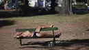 Seorang pria berjemur saat gelombang panas musim panas di bangku taman di Bosques de Palermo, Buenos Aires, Argentina (14/1/2022). Fenomena gelombang panas di Argentina sudah diperkirakan mencapai puncaknya pada minggu ini dengan temperatur mencapai 40 derajat celcius. (AP Photo/Mario De Fina)