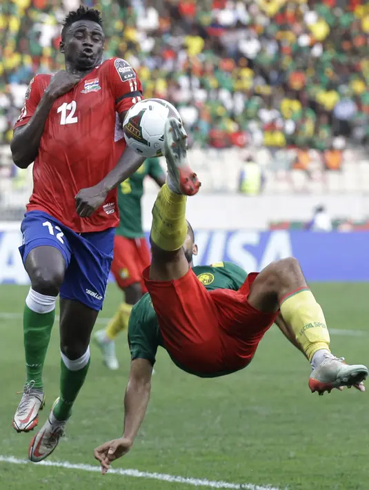 Bek Gambia James Gomez melakukan pertahanan saat bersaing dengan bek Kamerun JC Castelletto pada pertandingan perempatfinal Piala Afrika 2021 di Japoma Stadium, Minggu (30/1/2022) dini hari WIB. Kamerun melangkah ke semifinal usai menang atas Gambia, 2-0. (AP Photo/Sunday Alamba)