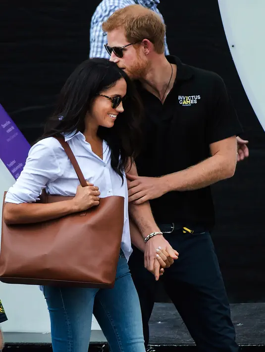 Pangeran Harry dan kekasihnya Meghan Markle bergandengan tangan saat menghadiri Invictus Games 2017 di Toronto, Kanada, Senin (25/9). Untuk kali pertama, keduanya menunjukkan kemesraan di depan publik. (Nathan Denette/The Canadian Press via AP)
