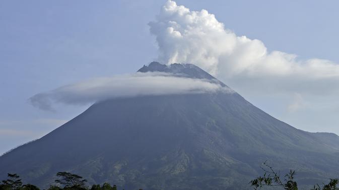 Gunung Merapi memuntahkan material  vulkanik dari kawahnya dilihat dari Sleman, Yogyakarta (7/1/2021). Kasbani mengatakan berdasarkan pantauan visual, Gunung Merapi terlihat jelas hingga tertutup kabut.  (AP Photo/Slamet Riyadi)