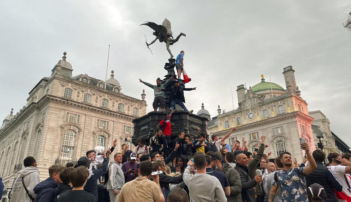 Suporter Inggris memanjat patung Eros di Piccadilly Circus saat merayakan kemenangan Inggris atas Jerman pada pertandingan babak 16 besar Euro 2020 di London, Inggris, Selasa (29/6/2021). nggris menang 2-0. (Isobel Frodsham/PA via AP)