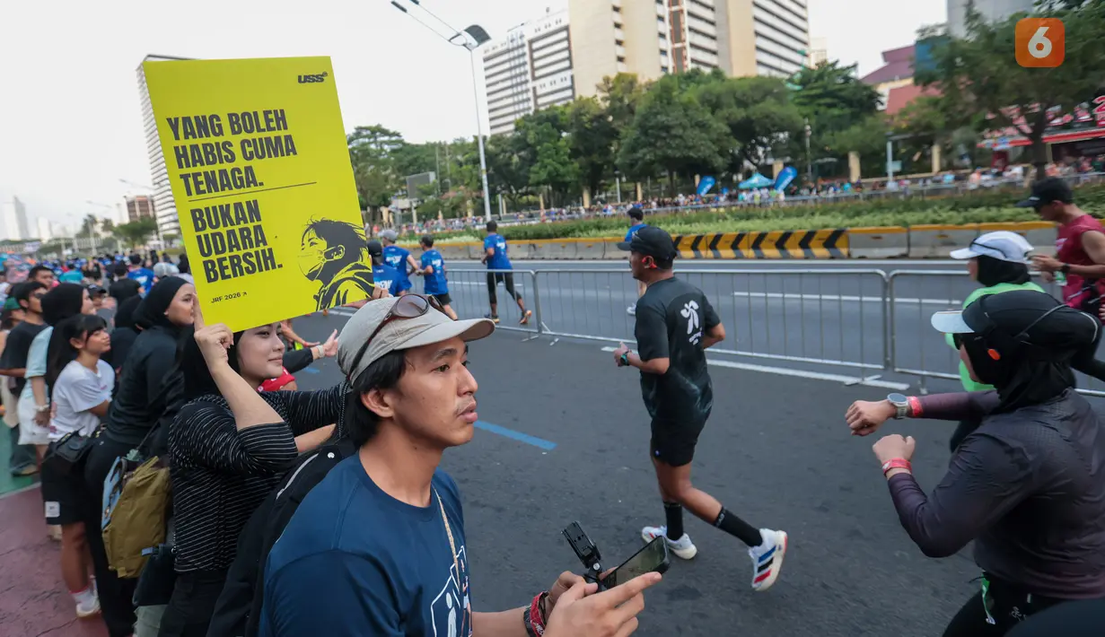 Seorang penonton membawa poster bertema kebakaran hutan dan lahan (karhutla) saat Jakarta Running Festival (JRF) 2026 di sepanjang lintasan Jalan Jenderal Sudirman, Jakarta, Sabtu (24/10/2026). (KLY/Budy Santoso)