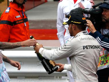 Pembalap Mercedes F1 Lewis Hamilton memberikan sampanye kepada penyanyi Justin Bieber usai berhasil menjuarai Grand Prix di Monaco, (29/5). Hamilton menjadi yang tercepat dengan mencatatkan waktu satu jam 59 menit 29,133 detik. (REUTERS/Eric Gaillard)