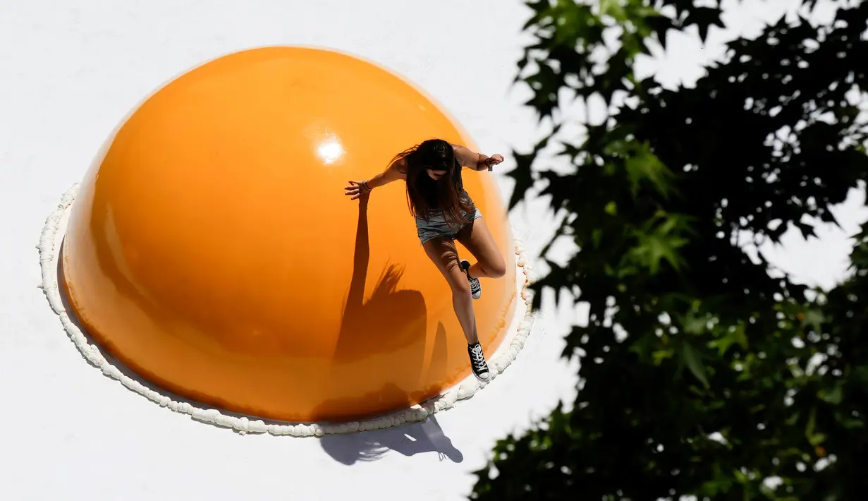 Seorang warga bermain di atas telur ceplok raksasa yang diletakkan di pusat kota Santiago, Chile, 8 November 2016. Telur mata sapi raksasa ini merupakan bagian dari festival seni Hecho en Casa. (REUTERS / Pablo Sanhueza)