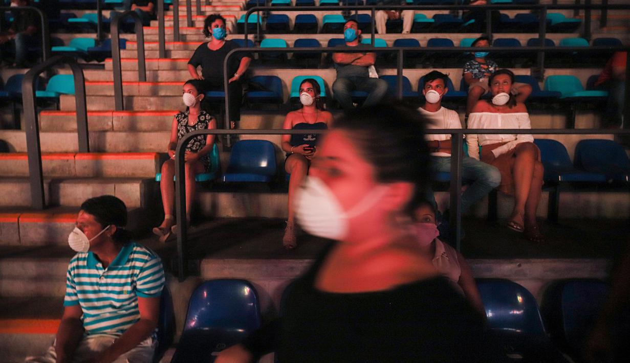Penonton mengenakan masker saat melihat pertandingan tinju yang dipromotori oleh mantan juara dunia Rosendo Alvarez di Managua, Nikaragua pada 25 April 2020. Nikaragua merupakan salah satu dari sedikit negara yang kegiatan olahraga tetap berjalan di tengah pandemi Covid-19. (AP/Alfredo Zuniga)