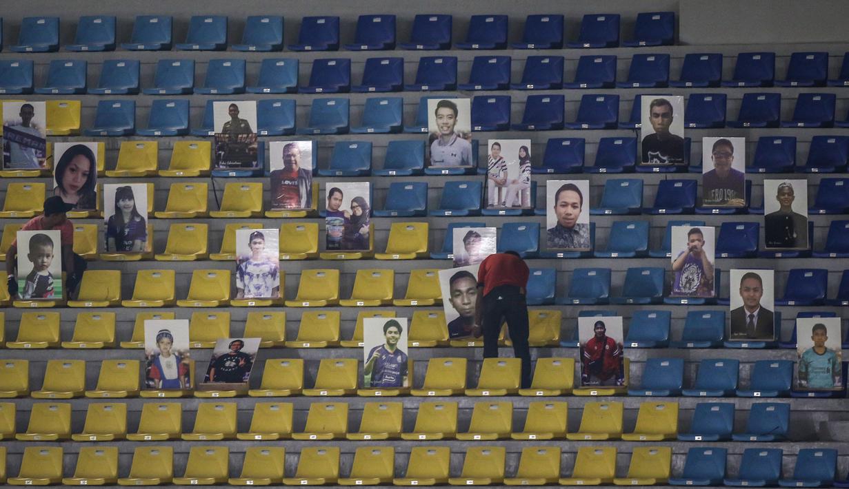 Sejumlah petugas melepas papan berwajah para fans Arema FC terlihat saat laga pekan kesebelas BRI Liga 1 2021/2022 antara Arema FC melawan Persebaya Surabaya di Stadion Manahan, Solo, Sabtu (06/11/2021). (Bola.com/Bagaskara Lazuardi)