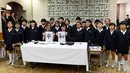 Negara AS Melania Trump (kiri) dan Istri PM Jepang, Akie Abe foto bersama para siswa sambil menunjukkan huruf kanji yang berarti "Damai" saat menghadiri kelas kaligrafi di sekolah dasar Kyobashi Tsukiji, Tokyo (6/11). (AFP Photo/Pool/Toshifumi Kitamura)