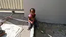 Shivani (15 bulan) duduk di tanah dengan kaki terikat pada batu di lokasi konstruksi di Ahmedabad, India, 20 April 2016. Ibunya, Sarta Kalara mengaku tak memiliki cara lain kecuali mengikatkan buah hatinya ke batu meskipun dia menangis (REUTERS/Amit Dave)