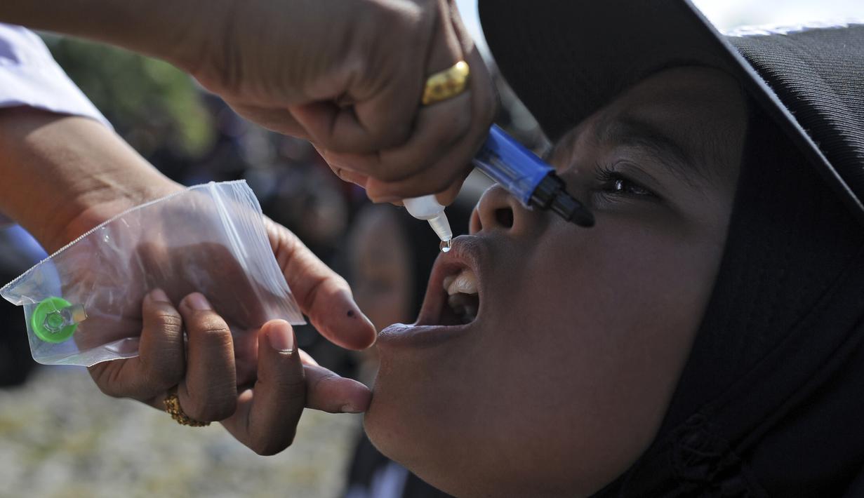 Seorang anak menerima imunisasi polio dari petugas medis saat berlangsung vaksinasi massal di Sigli Town Square,  Pidie, Aceh, Senin (28/11/2022). Kementerian Kesehatan melakukan vaksinasi massal sebanyak 1.000 anak dari target target 9.940 anak. (AP Photo/Riska Munawarah)
