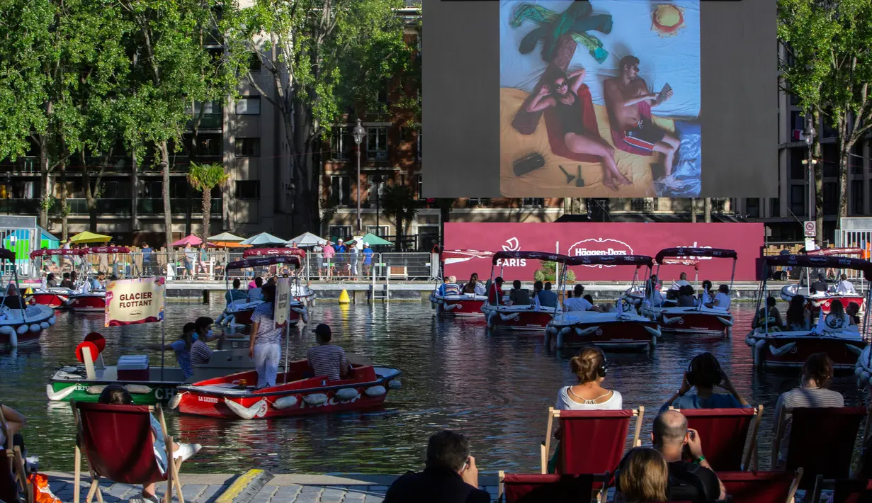 Orang-orang di atas kapal menghadiri Cinema on the Water, yang diselenggarakan Paris Plages selama pemutaran "Le Grand Bain" di Paris, Prancis pada 18 Juli 2020. Paris menghadirkan terobosan baru dengan bioskop terapung lengkap dengan perahu yang tetap menjaga jarak. (AP Photo/Rafael Yaghobzadeh)