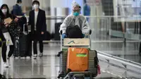 Penumpang mengenakan pakaian pelindung saat tiba di Bandara Internasional Hong Kong, Hong Kong (19/3/2020). Covid-19 yang menginfeksi lebih dari 200.000 orang terus menimbulkan kekhawatiran. (AFP/Anthony Wallace)