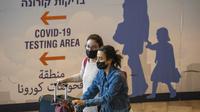 Pelancong yang mengenakan masker tiba di Bandara Ben Gurion dekat Tel Aviv, Minggu (28/11/2021). Israel pada Minggu menyetujui larangan masuknya warga negara asing dan penggunaan teknologi kontroversial untuk pelacakan kontak guna menekan penyebaran varian Omicron. (AP Photo/Ariel Schalit)