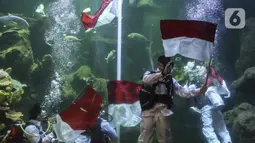 Penyelam mengibarkan bendera Merah Putih saat gladi resik HUT ke-75 RI dalam akuarium Sea World Ancol, Jakarta, Sabtu (15/8/2020). Taman Impian Jaya Ancol akan memperingati HUT ke-75 RI dengan mengibarkan bendera Merah Putih dalam akuarium Sea World pada 17 Agustus 2020. (Liputan6.com/Johan Tallo)