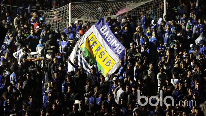 Aksi Bobotoh mengibarkan bendera dengan logo klub Persib Bandung. (Bola.com/Nicklas Hanoatubun)