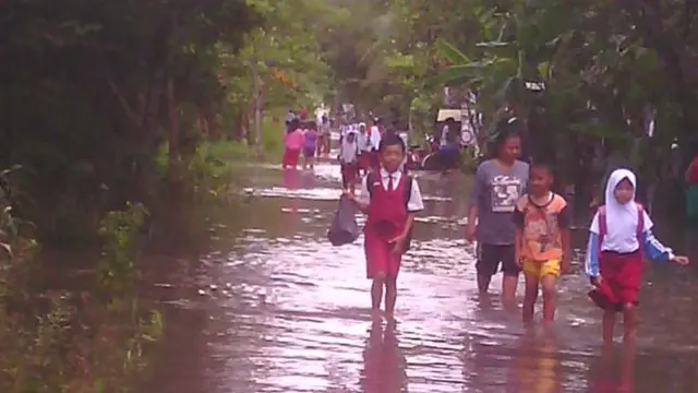 Anak-anak terpaksa mengarungi banjir untuk bersekolah. (Foto: Liputan6.com/BPBD Cilacap/Muhamad Ridlo)