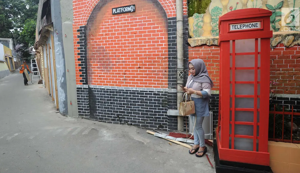Warga bermain handphone di samping kotak telepon di Gang Kepatihan, Jalan Veteran, Kebon Kelapa, Bogor Tengah, Bogor, Jawa Barat, Jumat (15/3). Gang Kepatihan mengusung tema internasional. (merdeka.com/Arie Basuki)