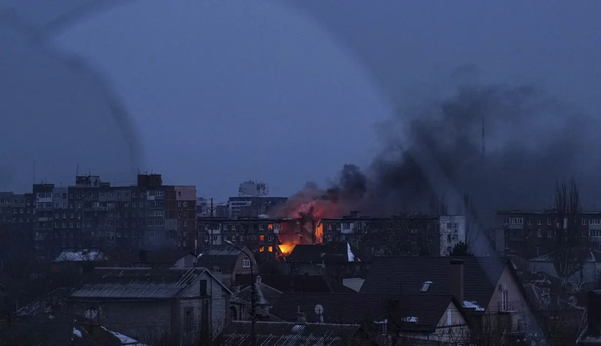Terlihat melalui jendela yang pecah, api membakar sebuah gedung apartemen setelah penembakan di sebuah distrik perumahan di Mariupol, Ukraina, 11 Maret 2022. Tepat pada hari ini, Kamis, 24 Maret 2022, invasi Rusia ke Ukraina sudah terhitung genap satu bulan penuh.  (AP Photo/Evgeniy Maloletka)