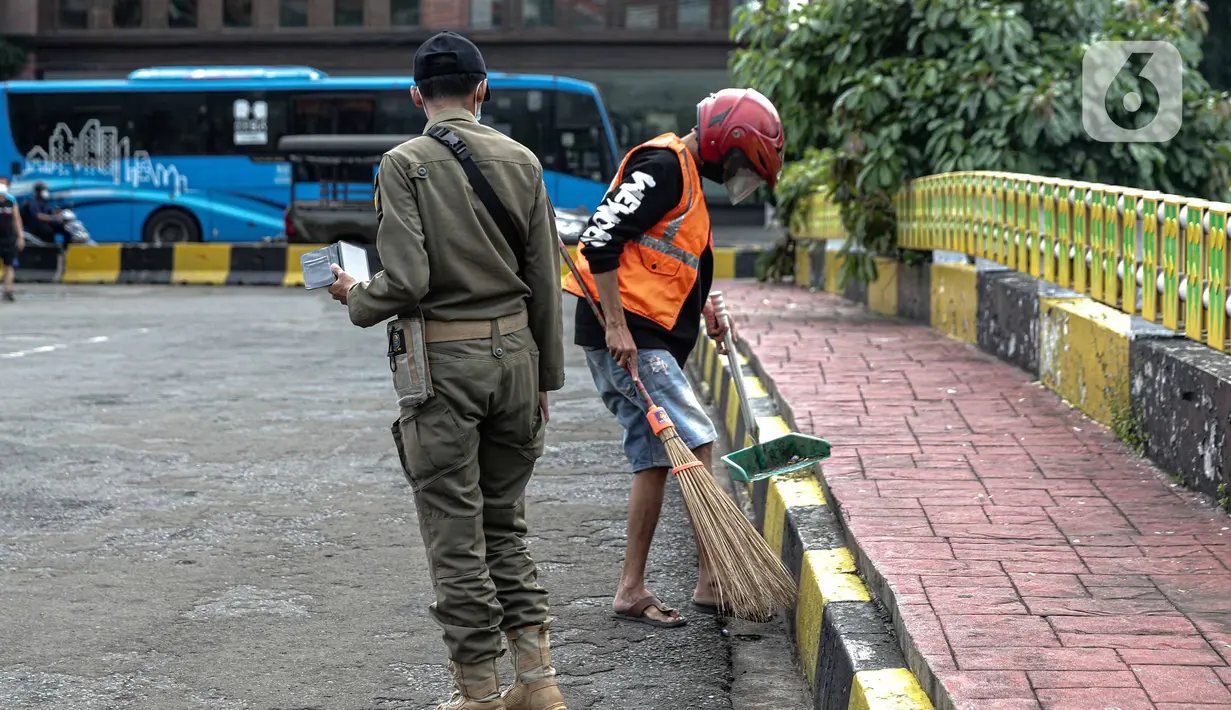 Petugas Satpol PP mengawasi warga yang menjalani sanksi sosial saat razia masker di kawasan Kota Tua, Jakarta, Kamis (24/2/2022). Perpanjangan PPKM level 3 untuk Jabodetabek berlaku selama sepekan, yakni sejak 22-28 Februari 2022 mendatang. (Liputan6.com/Faizal Fanani)