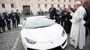 Paus Fransiskus saat menerima hadiah mobil Lamborghini Huracan di Vatikan, Rabu (15/11). Mobil Lamborghini ini oleh Paus rencananya akan dilelang dan hasilnya akan digunakan untuk membantu jemaah Kristen di Irak. (L'Osservatore Romano/Pool Photo via AP)