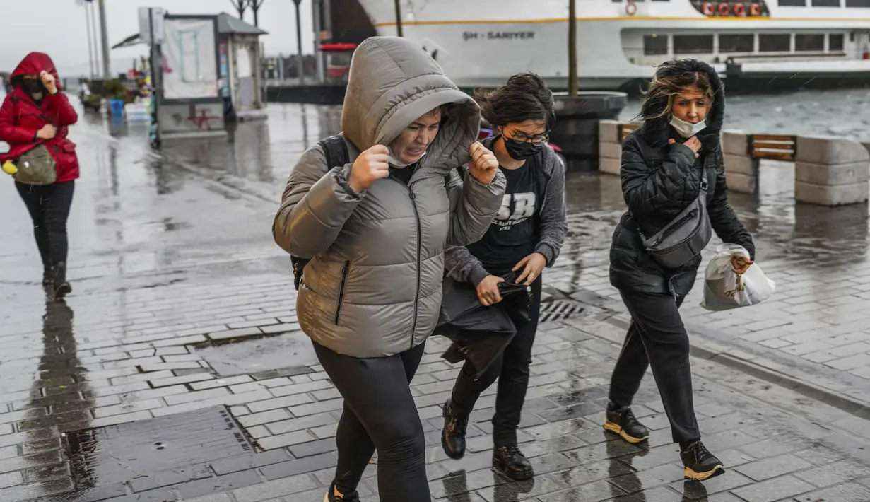 Orang-orang berlarian di bawah hujan deras selama hari badai di Istanbul, Turki, Senin (29/11/2021). Sedikitnya empat orang tewas pada Senin saat badai dahsyat disertai angin kencang menghantam kota metropolitan Istanbul di Turki, kata kantor gubernur Istanbul. (AP Photo)
