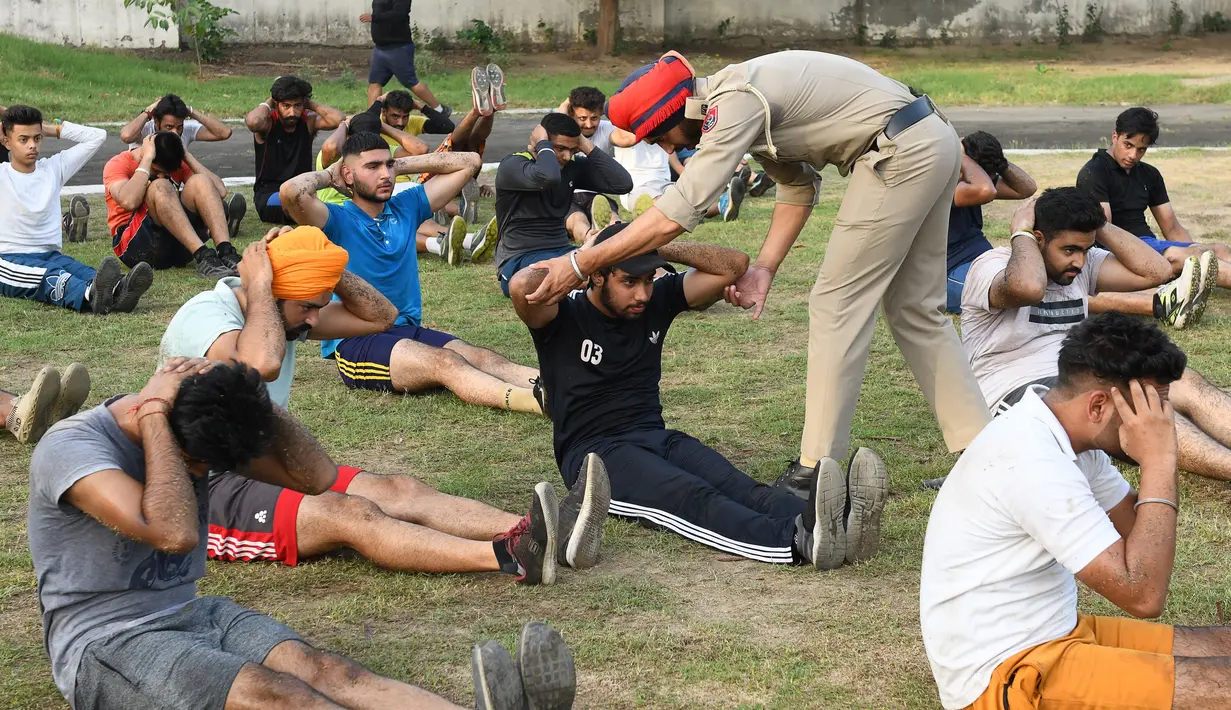 Pelatih polisi Punjab memandu seorang pemuda saat mengikuti pelatihan calon polisi Punjab di Amritsar, India, Senin (28/6/ 2021). (AFP/Narider Nanu)