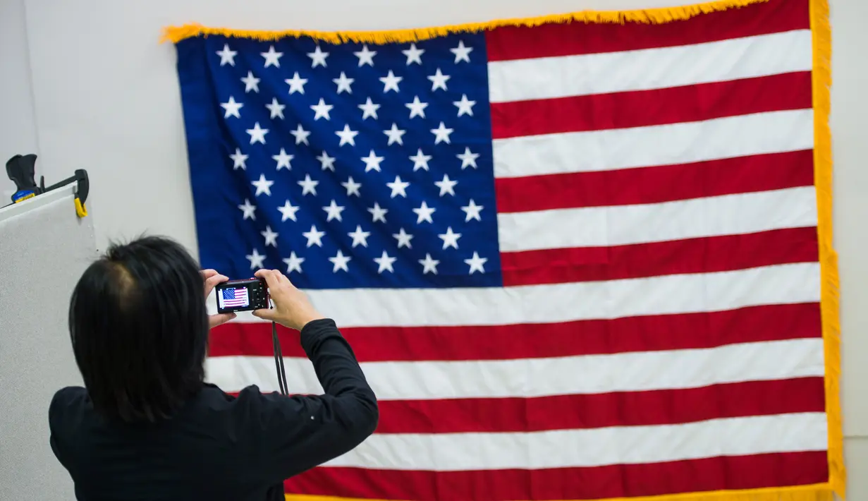 Pekerja memotret bendera Amerika Serikat di National Capital Flag Company, Alexandria Virginia, AS (10/1). Dalam acara tersebut Trump akan memberikan pidato resmi pertamanya sebagai presiden setelah membacakan sumpah. (AFP/Andrew Caballero Reynolds)