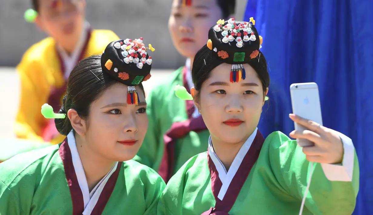 Dua gadis Korea Selatan berselfie saat mengikuti upacara Coming of Age Day di desa Hanan Namsan di Seoul (21/5). (AFP Photo/Jung Yeon-je)