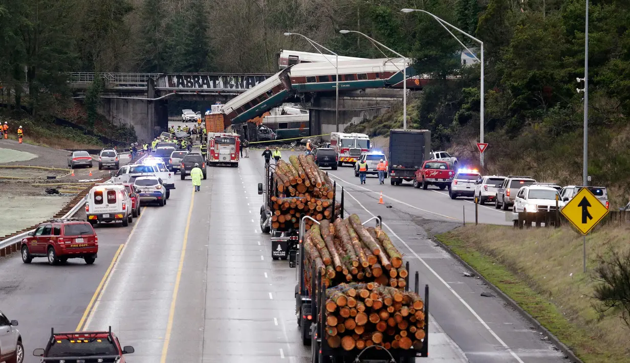Kereta Amtrak yang terjatuh dari jembatan dan menimpa kendaraan-kendaraan terlihat di jalan raya di Interstate di DuPont, Washington, AS (18/12). Hingga kini penyebab kecelakaan belum diketahui. (AP Photo / Elaine Thompson)