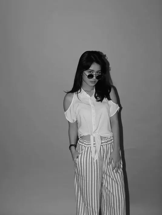 Kalau yang satu ini, Zulfa memakai celana kulot bermotif garis-garis dan crop top putih. Yang lebih kekinian adalah Zulfa memakai kacamata hitam yang hits banget serta rambut panjangnya yang dibiarkan terurai begitu saja. (Instagram/zulfamaharani)