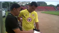 Pelatih kepala Pra PON Sumbar Delfi Adri (berdiri) melakukan evaluasi tim bersama Dirtek Suhatman Imam dalam sesi latihan di Stadion Agus Salim Padang beberapa waktu lalu. (Bola.com/Arya Sikumbang)