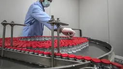 Pekerja laboratorium saat mengawasi produksi botol vaksin Sinovac di laboratorium Vacsera, Kairo, Mesir, Rabu (1/9/2021). Mesir berencana memproduksi satu miliar dosis Sinovac setiap tahun dan menjadikan produsen vaksin terbesar di Timur Tengah dan Afrika. (AFP/Khaled Desouki)