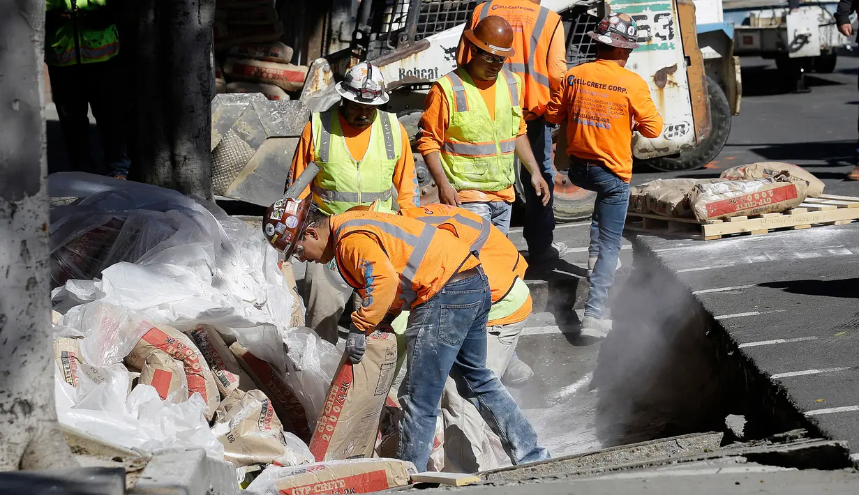 Pekerja memperbaiki jalan yang rusak akibat truk yang terjebak di San Francisco, AS, Jumat (5/5). Diduga karena muatan yang terlalu berat membuat bagian atas saluran pembuangan menjadi amblas. (AP Photo / Jeff Chiu)