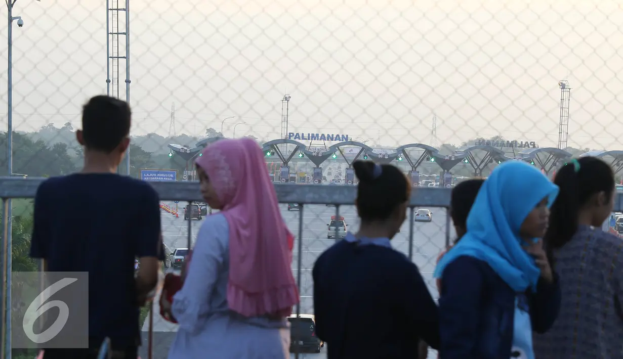 Warga melihat suasana arus mudik di Gerbang Tol Palimanan, Cirebon, Jawa Barat (9/7). Ramainya kendaraan yang melintas menjadi daya tarik warga untuk melihat bersama warga lainnya. (Liputan6.com/Herman Zakharia)