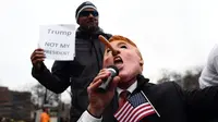 Aksi penolakan Donald Trump sebagai Presiden AS di Washington DC, Jumat (20/1). Seorang demonstran memakai topeng berwajah mirip Trump dengan hidung yang dipanjangkan. (AFP PHOTO / Jewel SAMAD)