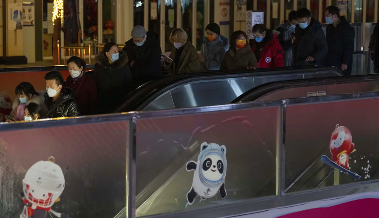Pengunjung menuruni eskalator untuk pergi saat mereka melewati antrean warga yang ingin membeli maskot Olimpiade Musim Dingin 2022 di luar Gongmei Emporium, Beijing, China, 8 Februari 2022. Antrean panjang sudah terjadi dalam beberapa hari terakhir. (AP Photo/Ng Han Guan)